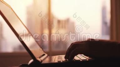 在日落时分，商人的<strong>手型</strong>`在城市建筑的大窗户旁的笔记本电脑上工作。 3840x2160